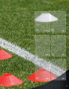 Albumseite des StickerStars-Musteralbums mit Spielersticker-Feldern vor unscharfem Trainingskegel auf dem Rasen