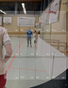 Albumseite des StickerStars-Musteralbums mit Spielersticker-Feldern vor unscharfem Hintergrund einer Sporthalle