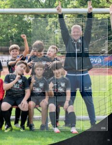 Albumseite des StickerStars-Musteralbums mit jubelnden Spielern und Trainer am Tornetz auf dem Sportplatz