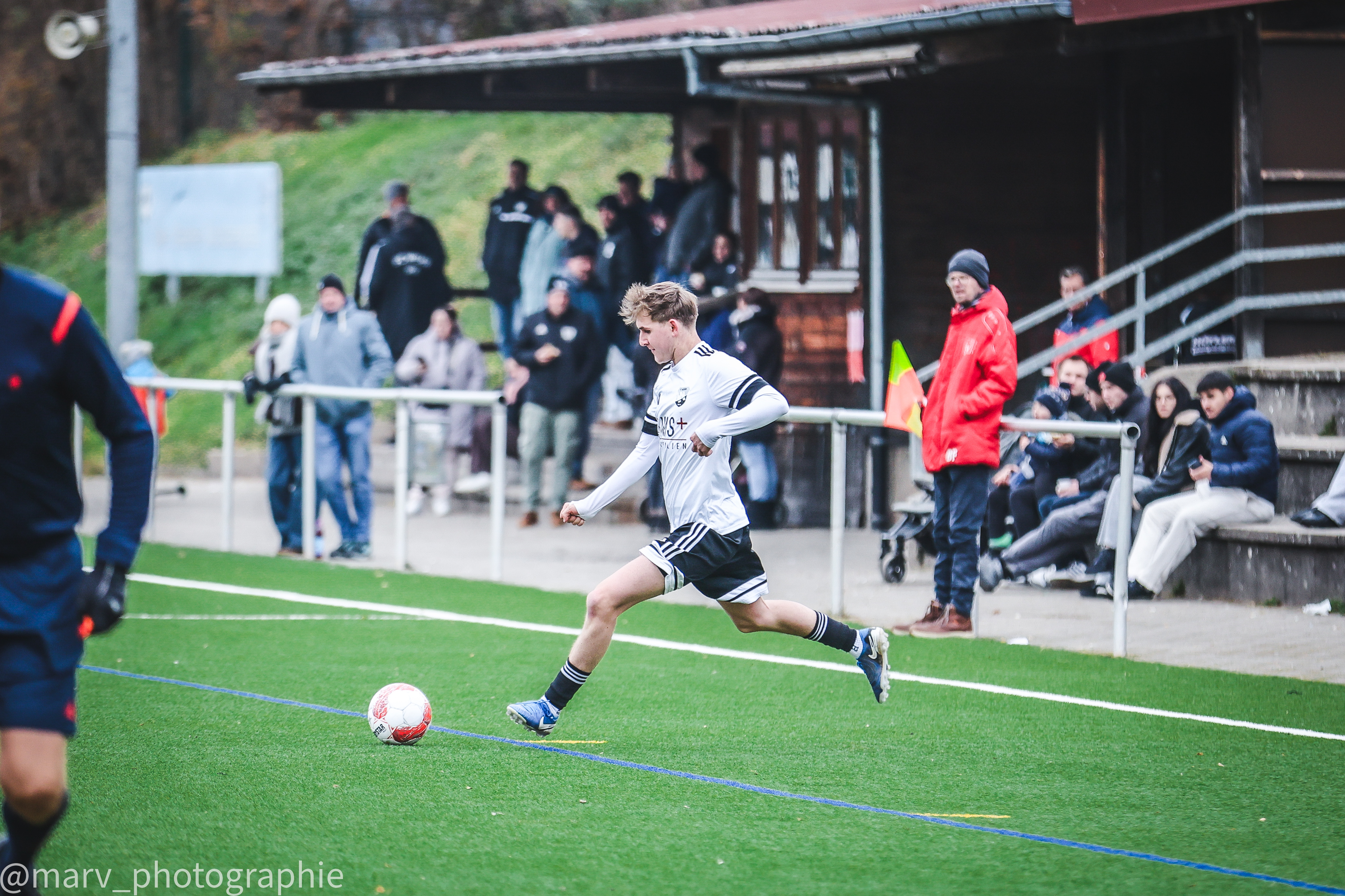 Spieler des FC Wehr 1912 e.V. am Ball vor Zuschauern entlang der Seitenlinie