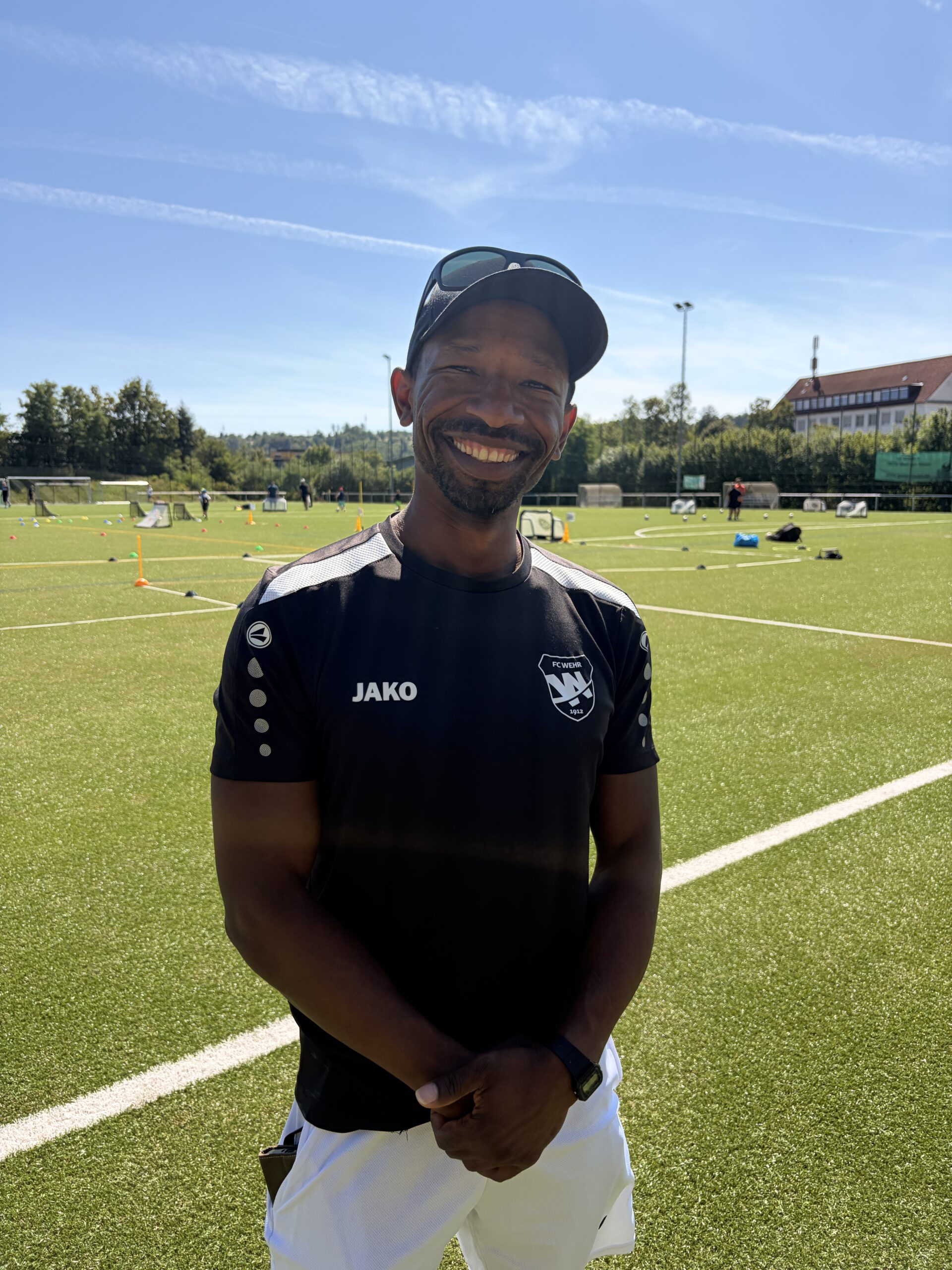 Lächelnder Trainer der G Junioren (U7) des FC Wehr 1912 mit Sonnenbrille auf dem Trainingsplatz