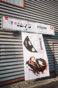 Werbebanner 'Hol' dir die Sticker des FC Wehr 1912' des StickerStars-2026-Projekts an der Fassade des REWE-Marktes