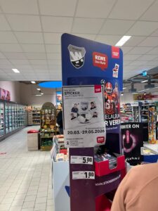 Werbedisplay für die StickerStars-2026-Aktion mit FC-Wehr- und REWE-Logo im Innenraum des Marktes
