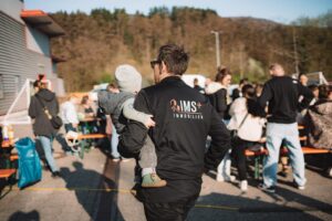 Vater trägt sein Kind auf dem Arm während der StickerStars-2026-Aktion vor dem REWE-Markt