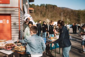 Besucher am Kuchenstand vor dem REWE-Markt während der StickerStars-2026-Aktion