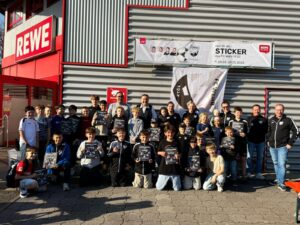 Großes Gruppenfoto der Nachwuchsmannschaften des FC Wehr 1912 vor dem REWE-Markt mit dem Sticker-Banner
