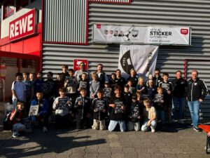 Großes Gruppenfoto der Nachwuchsmannschaften des FC Wehr 1912 vor dem REWE-Markt mit dem Sticker-Banner