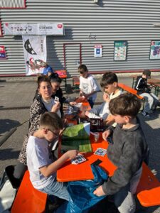 Familien sammeln StickerStars-2026-Sticker unter dem Sticker-Banner am REWE-Markt