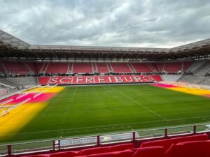 Tribunen mit SC-Freiburg-Schriftzug im Europa-Park Stadion mit farbiger Rasenbeleuchtung