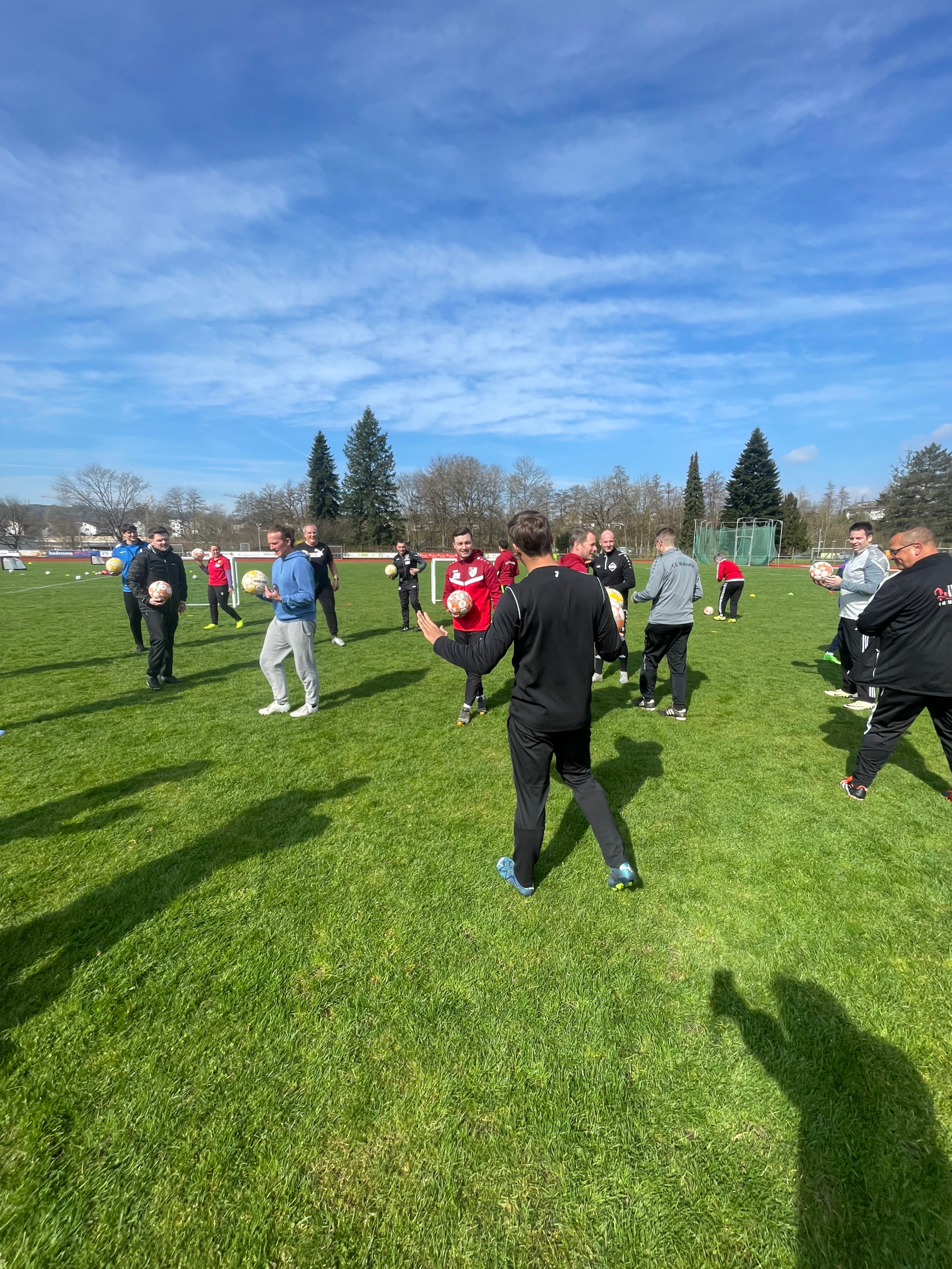 Gruppe von Trainern und Betreuern auf dem Sportplatz des FC Wehr 1912 bei blauem Himmel